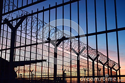 Barbed wire fence around a French immigration border with a beautiful colorful sky in the background located in Dieppe France Stock Photo