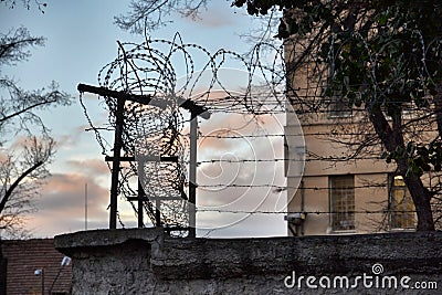 Barbed wire fence around prison walls Stock Photo