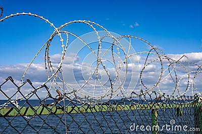 Barbed wire on the fence. Sea view Stock Photo