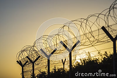 Barbed wire fence black silhouette on warm sunset sky background Stock Photo