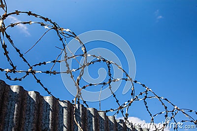 Barbed wire over a high fence protects against illegal entry Stock Photo
