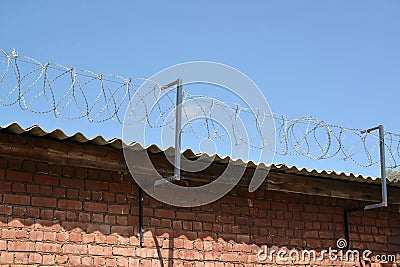 The barbed wire is tense over a brick wall Stock Photo