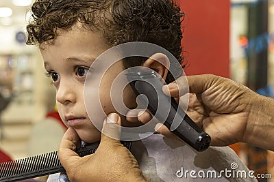 Barber cutting a child`s hair with curls Stock Photo