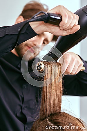 Barber dries the hair with the hair dryer of young, beautiful girl in a beauty salon Stock Photo