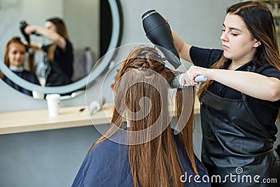 Barber dries his hair., cuts her hair to a girl with long hair. a woman dyes her hair, dries her hair with a hair dryer Stock Photo