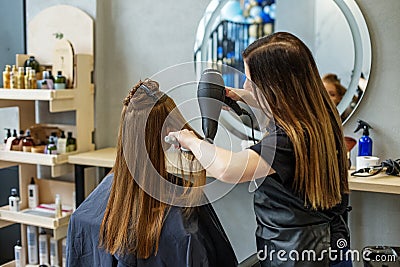 Barber dries his hair., cuts her hair to a girl with long hair. a woman dyes her hair, dries her hair with a hair dryer Stock Photo