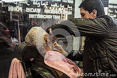 Barber shaving one of his client at night, in an old fashionned barber shop on the European side of the city Editorial Stock Photo