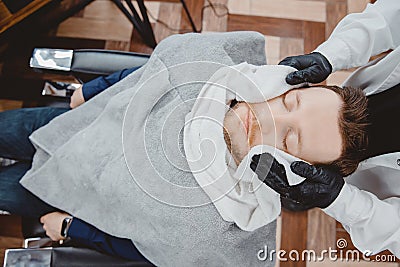 Barber steam face skin of man with hot towel before royal shave in Barbershop Stock Photo