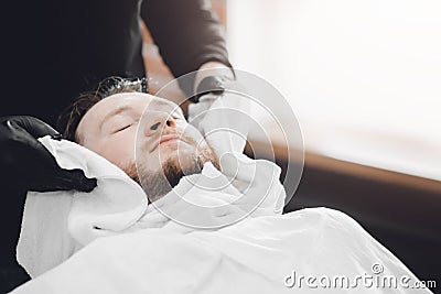 Barber steam face skin of man with hot towel before royal shave in Barbershop Stock Photo