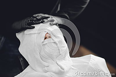 Barber steam face skin of man with hot towel before royal shave in Barbershop Stock Photo