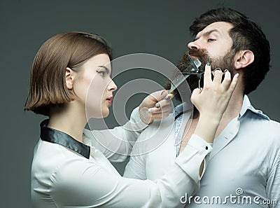 Barbershop or hairdresser concept. Woman hairdresser cuts beard with scissors. Guy with modern hairstyle visiting Stock Photo