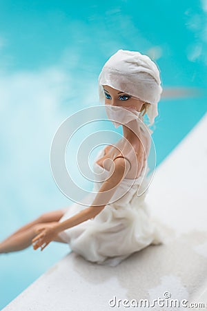 Barbie doll sitting in border swimming pool with amedical mask Editorial Stock Photo