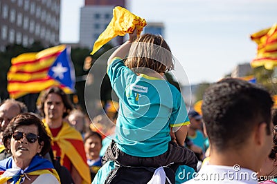 Little girl holding a flag with ANC pro-independence shirt over his father`s shoulders. Rally at La Diada, Catalonia`s National Editorial Stock Photo