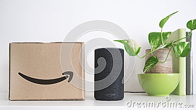 BARCELONA - SEPTEMBER 2018: Amazon Echo Smart Home Alexa Voice Service next to an order in a cardboard box on a shelf. Some books Editorial Stock Photo