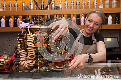 Barcelona, Spain - April 5, 2016: Attractive young woman give cup of tea in transparent glass prepared with russian traditional tr Editorial Stock Photo