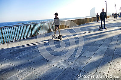 Barcelona Spain seafront perspective view of two children driving hoverboards Editorial Stock Photo