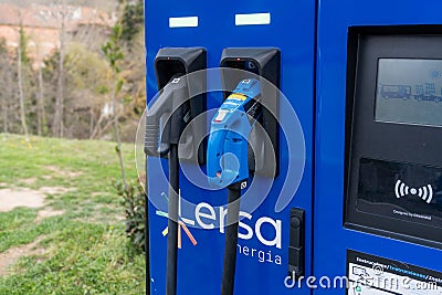 Barcelona, Spain-29 March 2024. A blue and green charging station for electric cars. The station is located in a grassy area. Editorial Stock Photo