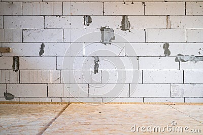 A bare aerated concrete brick wall and an oriented strand board floor. Background from an unfinished house with bare walls. Room Stock Photo