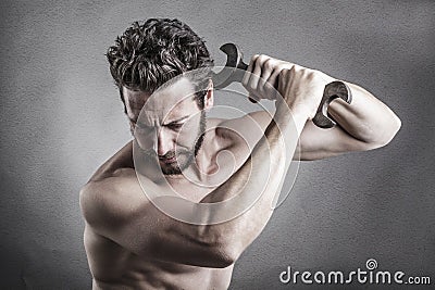 Bare chest man using a spanner or wrench as a weapon Stock Photo