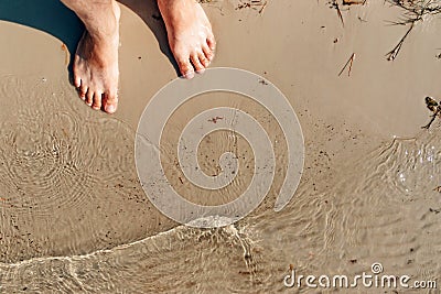 Bare feet of feet on yellow sea sand, wave. View from above. The concept of vacation, summer, vacation, vacation at sea, summer. Stock Photo