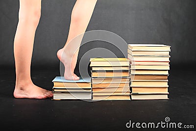 Bare feet of teenage girl stepping on old books Stock Photo