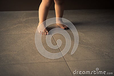 Barefoot baby are staying on heating tile floor Stock Photo