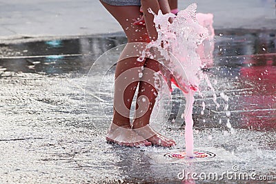 Barefoot girl touching the fountain on the sidewalk in the evening Stock Photo