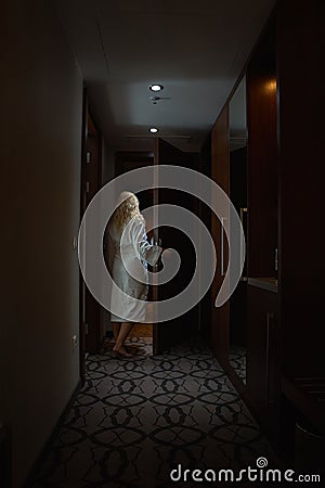 Barefoot Woman with white Bathrobe open the Door Stock Photo