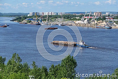 A barge carries cargo on the river. Transportation of wood by river transport. Stock Photo