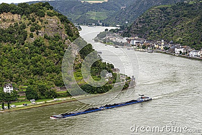 A barge with coal sailing on the river Rhine in western Germany, visible buildings on the river bank, aerial view. Stock Photo