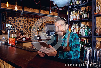 The barista barma with a tablet is smiling at workplace in bar Stock Photo