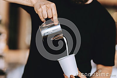 Barista carefully pours the milk into a glass in a modern coffee shop. Stock Photo