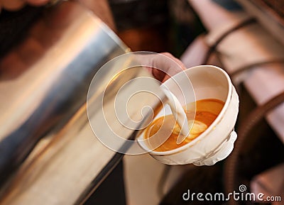 Barista in coffee bar preparing proper cappuccino pouring frothed milk into cup of coffee, making latte art, pattern Stock Photo