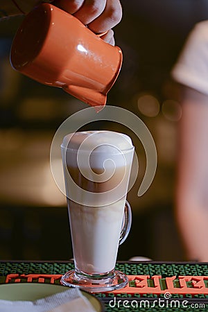 Barista creating latte art on long coffee with milk. Latte art in coffee mug. Barman pouring fresh coffee. Editorial Stock Photo