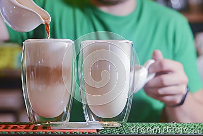 Barista creating latte art on long coffee with milk. Latte art in coffee mug. Barman pouring fresh coffee. Stock Photo