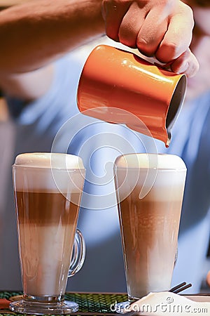 Barista creating latte art on long coffee with milk. Latte art in coffee mug. Barman pouring fresh coffee. Stock Photo