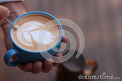 Barista creating pattern in cup of coffee on blurred background, closeup. Space for text Stock Photo