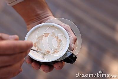 Barista creating pattern in cup of coffee on blurred background, closeup. Space for text Stock Photo