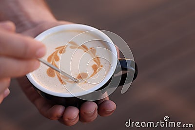 Barista creating pattern in cup of coffee on blurred background, closeup. Space for text Stock Photo