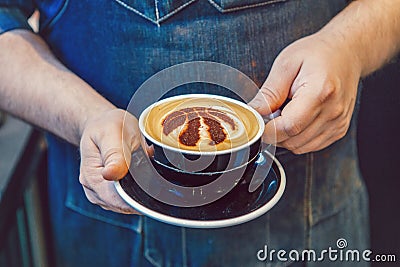 Barista hands holding black cup of coffee cappuccino with Toronto Raptors basketball team logo sign on milk foam Editorial Stock Photo