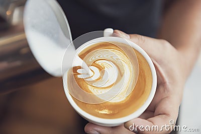 Barista making latte or Cappuccino art with frothy foam, coffee cup in cafe Stock Photo