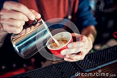 Barista man creating latte art on long coffee with milk. Latte art in coffee mug. Barman pouring fresh coffee Stock Photo