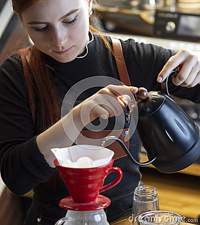 Barista pouring boiling water of manual drip brewer and make coffee. Girl pouring on coffee ground with filter. Alternative pure Stock Photo