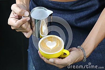 Barista pouring milk foam for making coffee latte art with pattern the heart in a cup Stock Photo