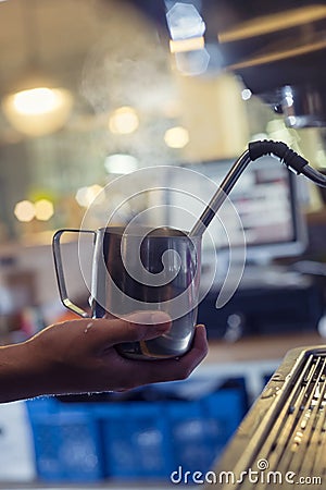 Barista prepares a cappuccino latte on a coffee machine in a cafe, steaming milk Stock Photo