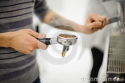 Barista with tattoo holding a temper with coffee Stock Photo