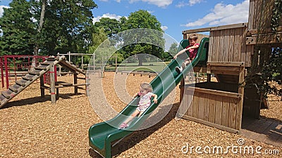 Wood chippings and children sliding down a green slide Stock Photo