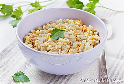 Barley porridge in a bowl with meat, vegetables and green parsley Stock Photo