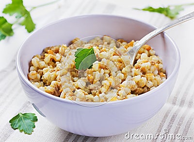 Barley porridge in a bowl with meat, vegetables and green parsley Stock Photo