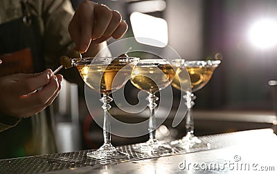 Barman adding olives to martini cocktail on counter. Space for text Stock Photo